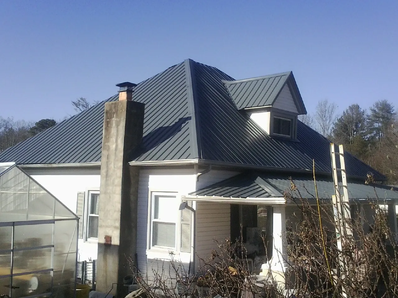 Dark blue standing seam metal roof on a white farmhouse with dormer — Slate & Tile Roof Repair by Roofing Brothers in Central Point