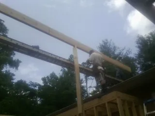 Carpenter setting a ridge beam over a new addition frame — Ice Dam Removal by Roofing Brothers in Central Point