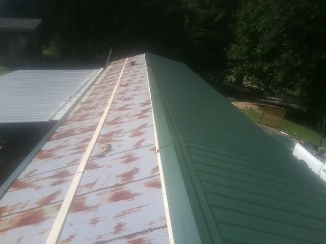 Old rusted panels beside newly installed green metal roofing — Wind Damage Roof Repair by Roofing Brothers in Central Point