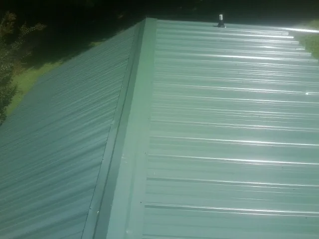 New green metal panels meeting at the ridge of a roof — Flat Roof Repair work by our crew in Central Point