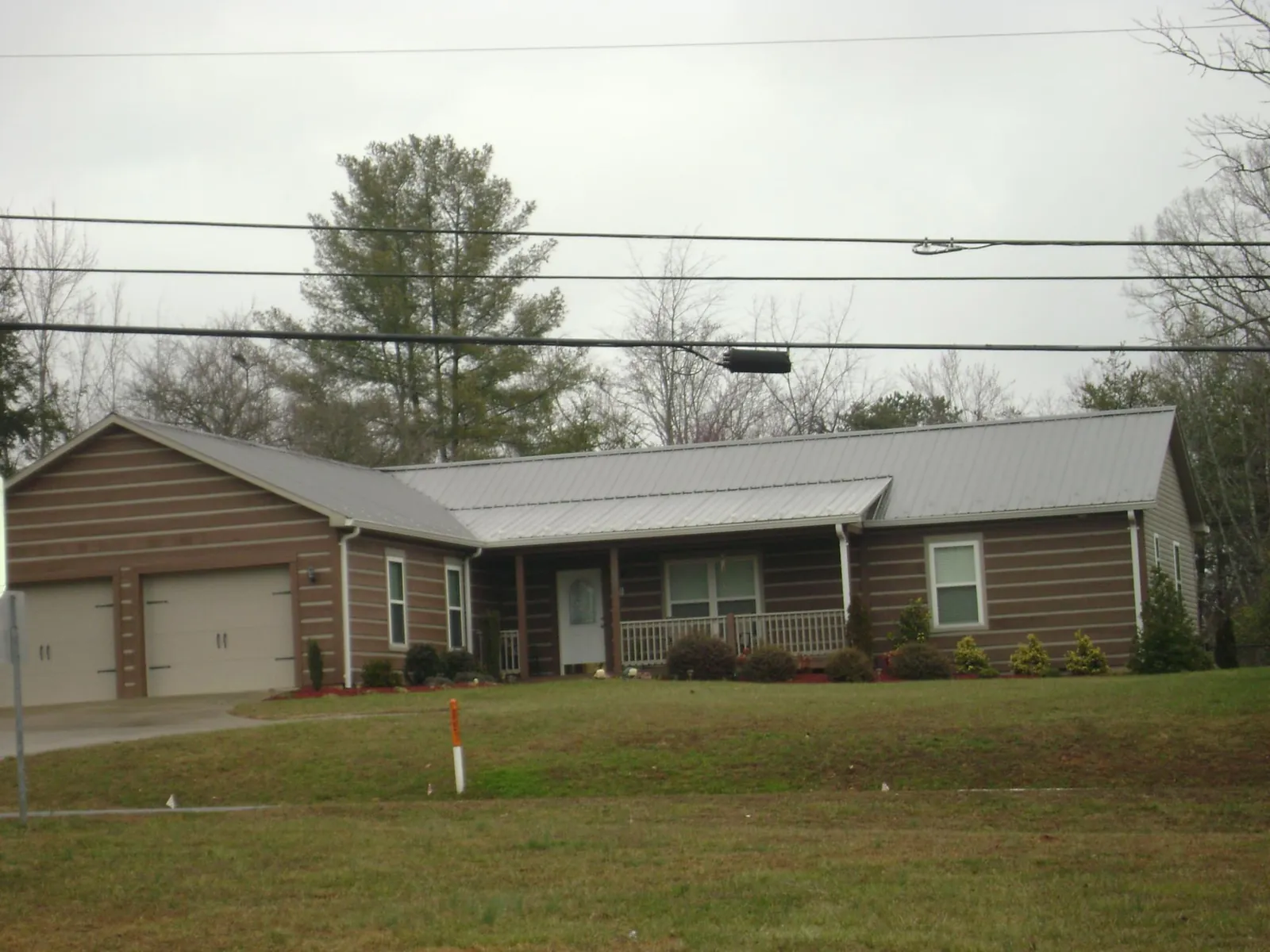 Gray metal roof on a log sided ranch home with a front porch in Central Point