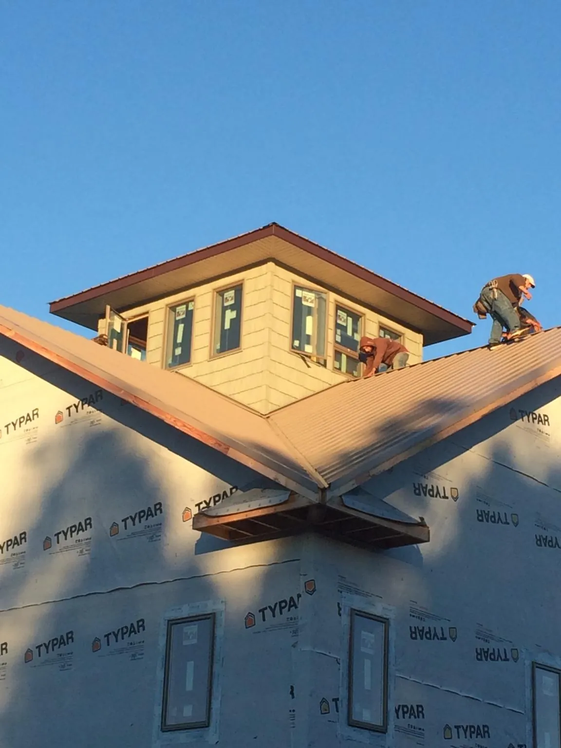 Roofers working around a rooftop cupola on a new metal roof at sunset — Roof Waterproofing in Central Point by Roofing Brothers